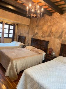 a bedroom with three beds and a chandelier at Hotel Casa Victoria in Antigua Guatemala