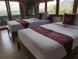 twee bedden in een kamer met een groot raam bij Mountview Bali in Kubupenlokan