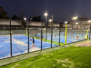 a group of people playing tennis on a tennis court at night at Piso con AC, piscina y pista de pádel y tenis en Águilas in Águilas