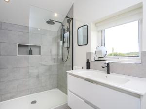 a white bathroom with a sink and a shower at Swn Y Mor in Benllech +26 photos