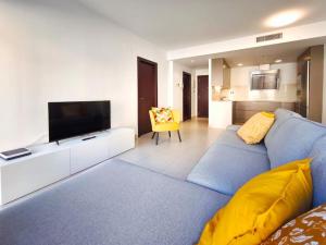 a living room with a blue couch and a flat screen tv at Moderno Apartamento Dúplex en Terrassa Centro in Terrassa