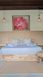 a bedroom with a large bed with a flower painting on the wall at Pondok loji in Ubud +24 photos