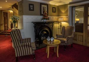 a living room with two chairs and a table and a fireplace at Percy French Hotel in Strokestown