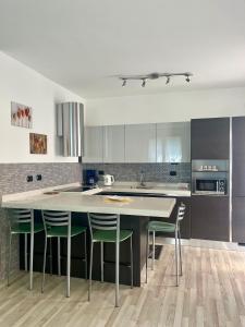 a kitchen with a large island with green chairs at Casa vacanze Sissi in Arco