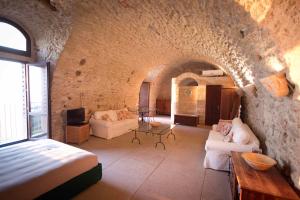 Habitación con cama y sofá en una pared de piedra. en Il Convento della Pietà, en Tropea