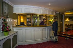 a woman standing at a bar in a hotel at Percy French Hotel in Strokestown