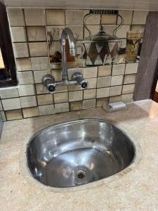 a silver sink in a kitchen with a tiled wall at LUXE 2 BR Apartment Spacious And Modern Lounge in Karachi