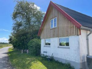 a white house with a red roof next to a road at Hygge Havn in Åkirkeby
