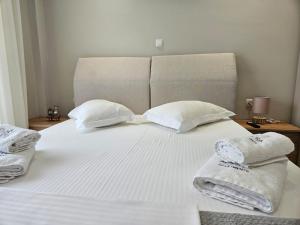 Una cama blanca con dos toallas encima. en Agora luxury Flat 2, en Loutraki