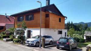 two cars parked in front of a house at Apartments Maroflin in Crni Lug