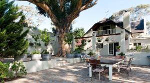 a table and chairs in front of a house with a tree at Kloofzicht Estate Country House in Tulbagh