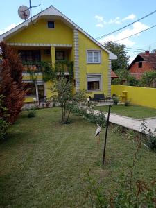 a yellow house with a bird standing in the yard at Apartman Zivic in Berilovac +18 photos