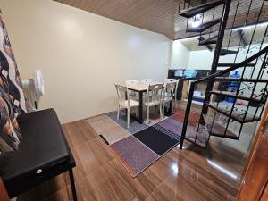a dining room with a table and a spiral staircase at The Catolico's Transient House in Baguio
