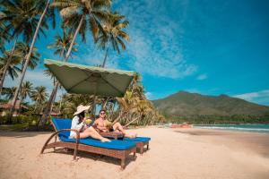 a group of people sitting on a beach under an umbrella at Daluyon Beach and Mountain Resort in Sabang