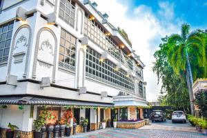 a large white building on a street with a palm tree at Hotel Grand Bandara in Medan