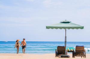 a man and woman standing on the beach under an umbrella at Daluyon Beach and Mountain Resort in Sabang