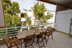 a wooden table and chairs on a balcony at Athenian Riviera Varkiza next to the beach in Vari