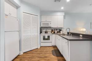 cocina blanca con electrodomésticos blancos y suelo de madera en Harbour House at the Inn Unit 205 condo, en Fort Myers Beach