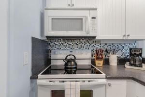cocina blanca con fogones y microondas en Harbour House at the Inn Unit 205 condo, en Fort Myers Beach 19 fotos más
