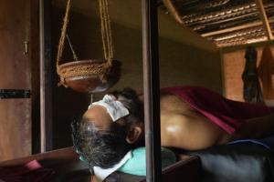 a man sleeping on a bed with a towel on his head at Ama Villa - Habarana in Habarana