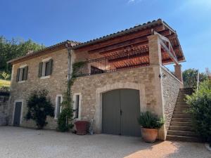 une grande maison en briques avec un garage et des escaliers dans l'établissement Les Noyers, à Montjustin