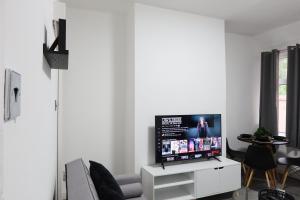 a living room with a flat screen tv on a white cabinet at Beeston House Manchester in Manchester