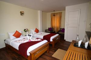 a hotel room with two beds and a window at Yagappa Heritage Resort - Near Lake & Bus Stand in Kodaikānāl +128 photos