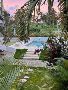 a swimming pool in a garden with flowers and plants at Ballenas beach C8 in Las Terrenas