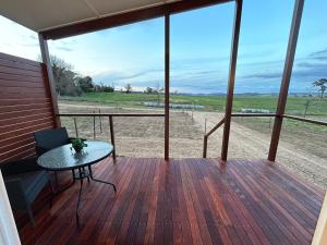 a porch with a table and a view of a field at Red Hill Cabin #1 Walcha in Walcha