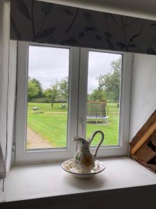 a vase sitting on a window sill next to a plate at The Stable in Sourdeval