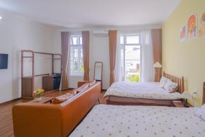 ein Hotelzimmer mit zwei Betten und einer Couch in der Unterkunft Mô Tê Homestay 2 gần Chợ Đông Ba, Cung Đình Hoàng Thành Huế in Hue