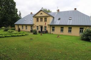 KazdangaParka nams的一栋黄色的大房子,院子里有两只猫