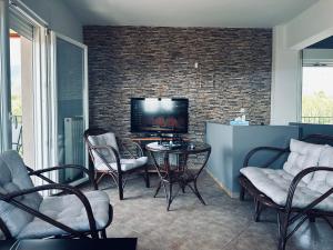 un salon avec une télévision, une table et des chaises dans l'établissement Villa George, à Leptokaryá