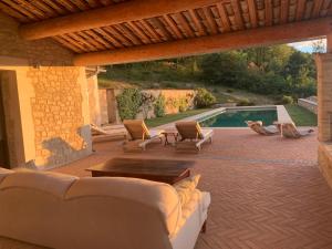 une terrasse avec un canapé, une table et une piscine dans l'établissement Les Noyers, à Montjustin