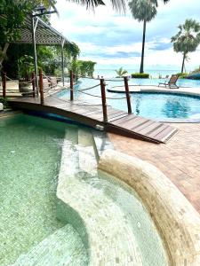 a swimming pool with a wooden deck in the water at The Palm Wongamat 22 in North Pattaya