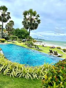 a swimming pool next to a beach with palm trees at The Palm Wongamat 22 in North Pattaya