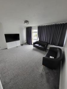 Una sala de estar con dos sillas y un sofá y un televisor. en Elm Park Home with Garden & Parking, en Hornchurch