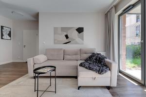 a white living room with a couch and a table at Scala City Center Apartments & Studio by Lion Apartments in Gdańsk