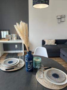 Una mesa con dos platos y un jarrón azul con plumas. en Volt Air Roof Top - Wifi - Parking privé - Proche Gare, en Troyes 4 fotos más