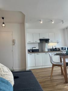 una cocina con armarios blancos y una mesa con una silla en Volt Air Roof Top - Wifi - Parking privé - Proche Gare, en Troyes