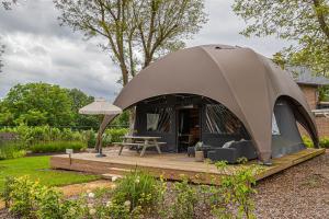 a tent in a garden with a table and chairs at Glampinglodge Jasmijn met privé hottub in Meerssen