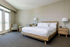 a bedroom with a large white bed and a chair at Balcomo, a Ramada by Wyndham in Penticton +195 photos