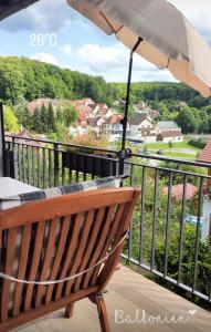 a wooden bench sitting on a balcony with an umbrella at Zimmer im Herzen Gößweinsteins in Gößweinstein