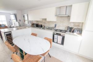 eine weiße Küche mit einem Tisch und Stühlen in der Unterkunft Holiday home in Portrush West Strand beach in Portrush