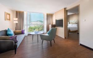 a hotel room with a couch and a tv and a bed at DoubleTree Resort by Hilton Hotel Penang in Batu Ferringhi
