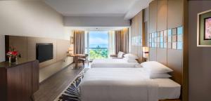 a hotel room with three beds and a television at DoubleTree Resort by Hilton Hotel Penang in Batu Ferringhi