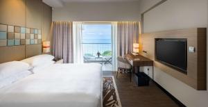 a hotel room with a bed and a desk and a television at DoubleTree Resort by Hilton Hotel Penang in Batu Ferringhi