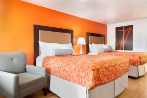 two beds in a room with an orange wall at Howard Johnson by Wyndham Harrisonburg in Harrisonburg
