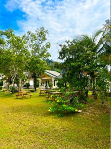 une aire de pique-nique avec des tables de pique-nique et des arbres dans l'établissement TC Garden Resort, à Kuah