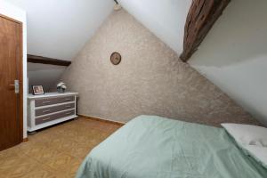 a attic bedroom with a bed and a dresser at Agréable maison de ville in Vincelles